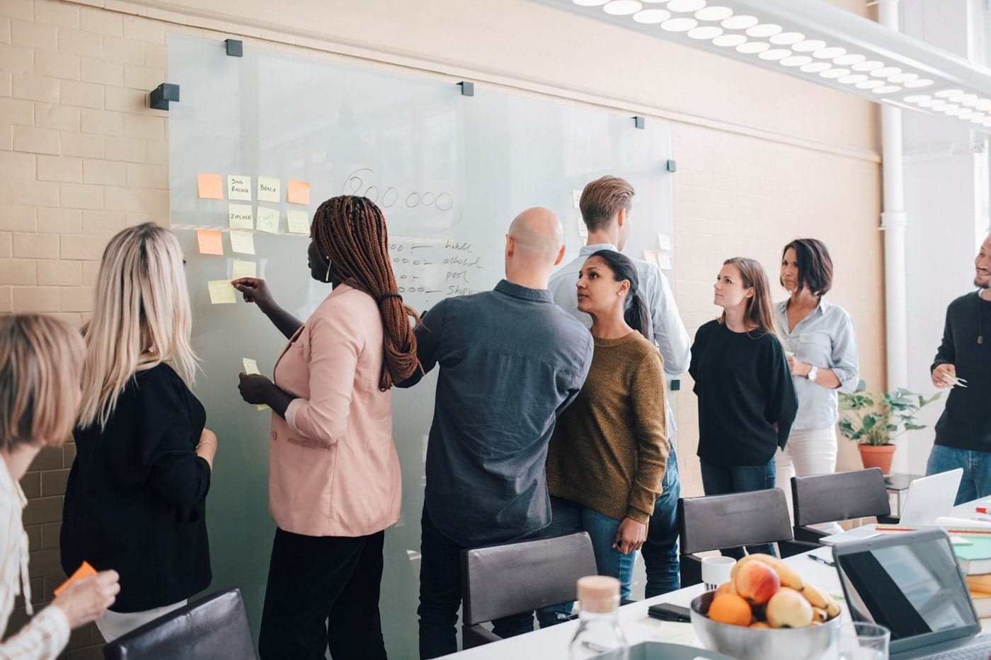 white-board-team-work A team gathered around a whiteboard filled with notes and diagrams, collaborating and discussing ideas during a brainstorming session.